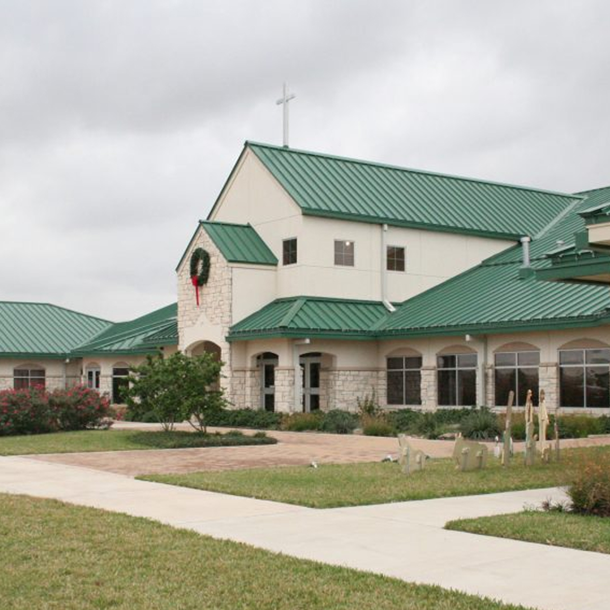Light colored stone front of Grace Lutheran Church with green roof, located in Victoria, Texas.