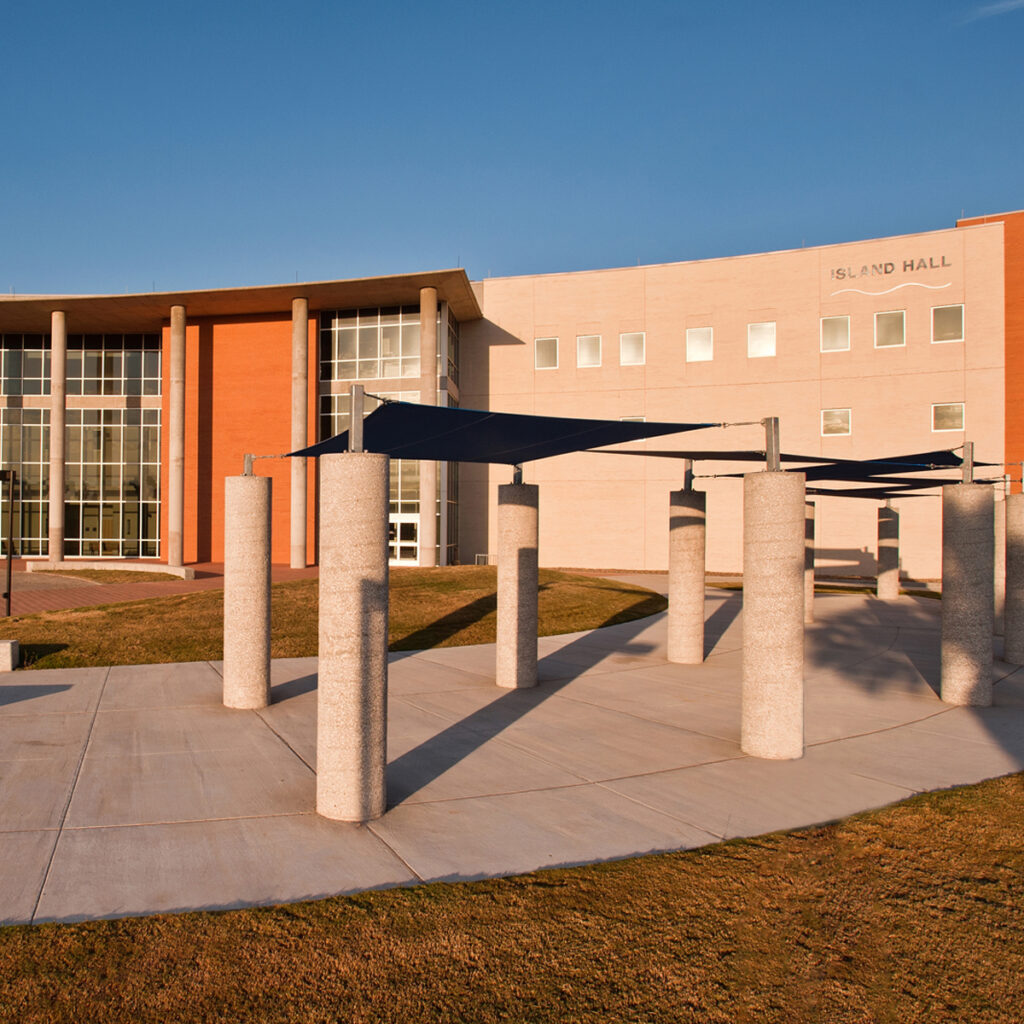 Outside view of Island Hall at Texas A&M University in Corpus Christi, Texas. Glass and brick exterior with concrete columns and shade covers.